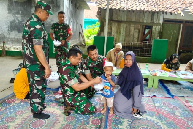 Danramil beserta Babinsa membantu kader dan bidan desa melaksanakan Posyandu Balita